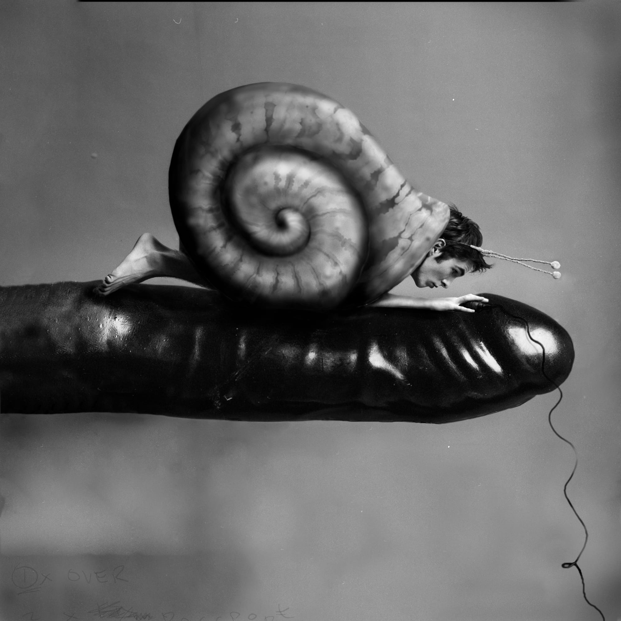 Self-portrait as an infant on the back of a huge snail on a giant fingertip, antennae on the head.
