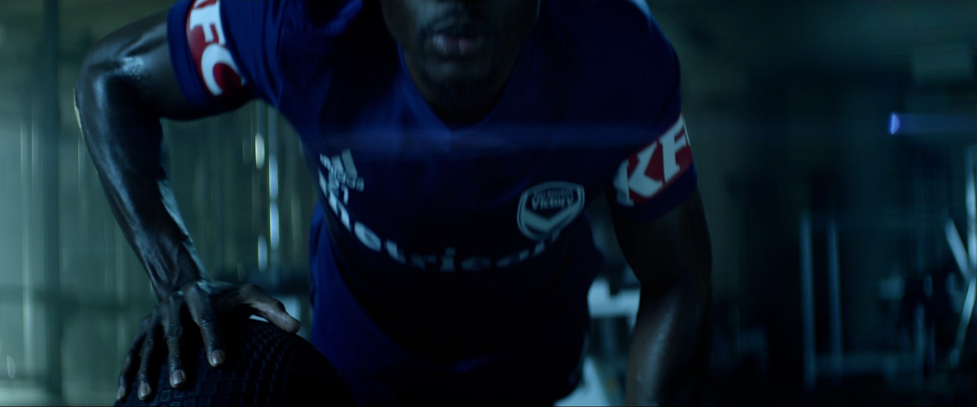 Close on a player in the club's navy kit, crouched and focused under hard gym light.