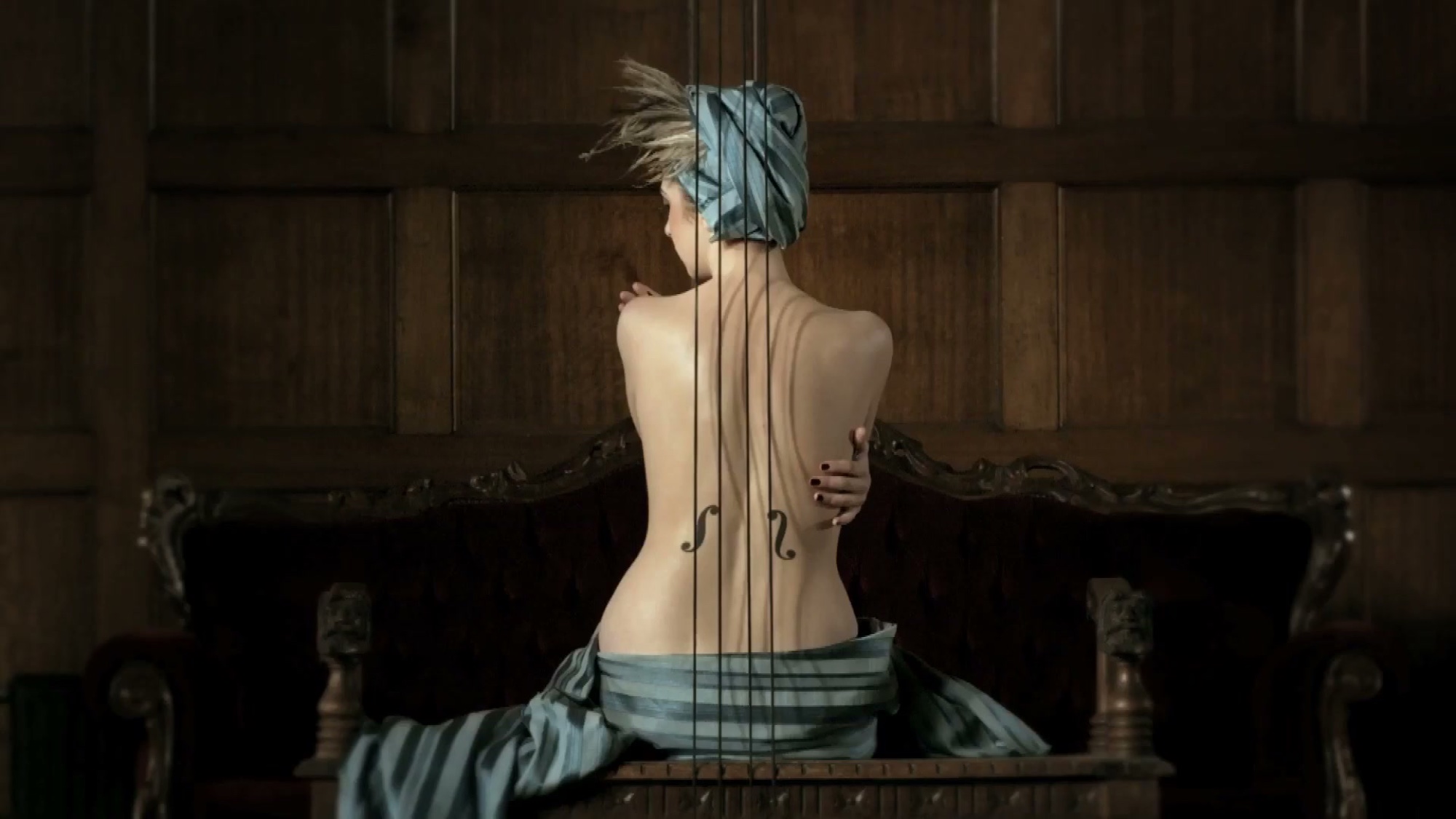A woman seen from behind, her bare back strung vertically with cello strings like a human instrument, a blue headwrap and striped cloth, seated on a carved wooden settee against dark panelling