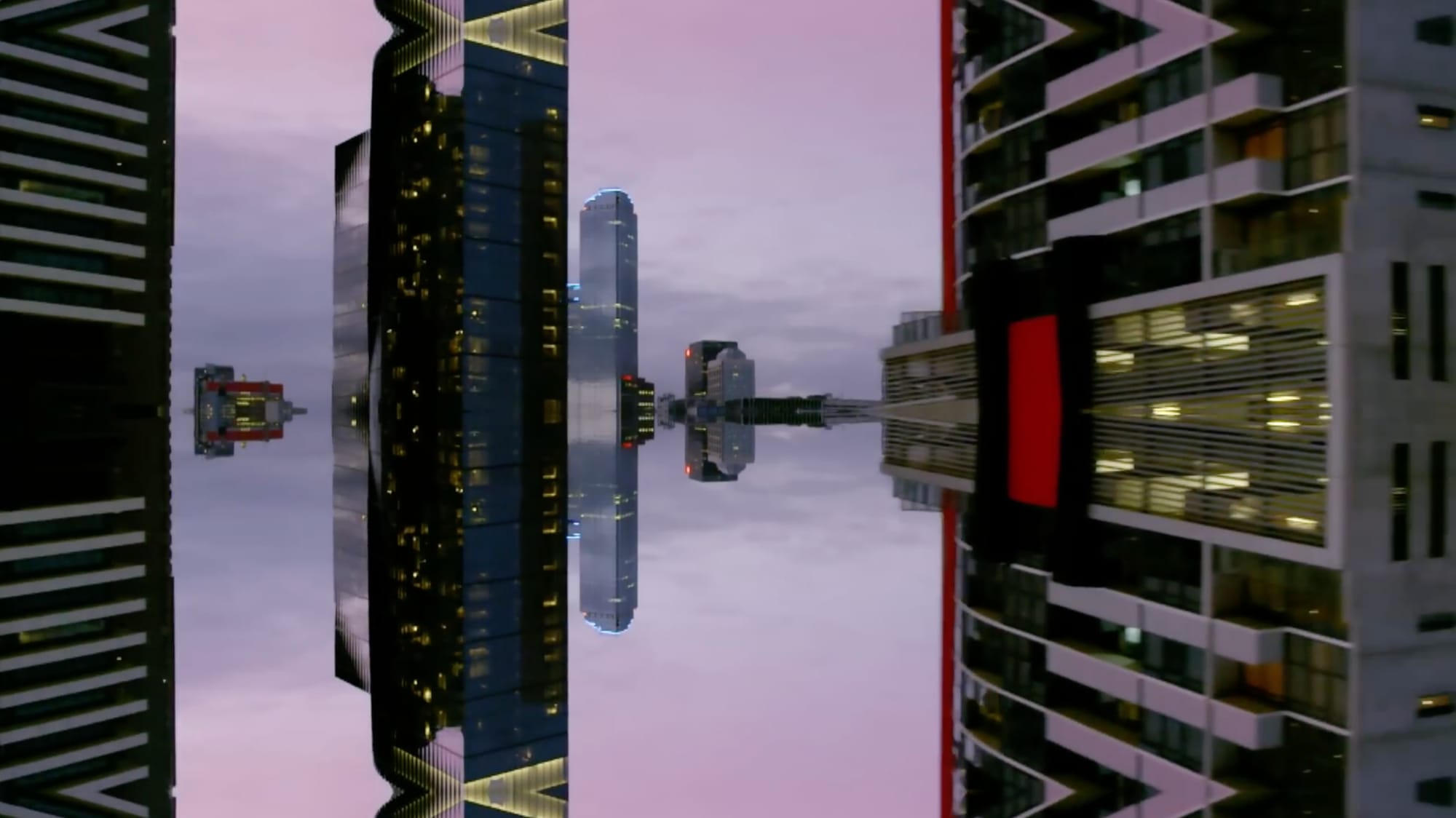 Office towers mirrored and inverted against a pink evening sky