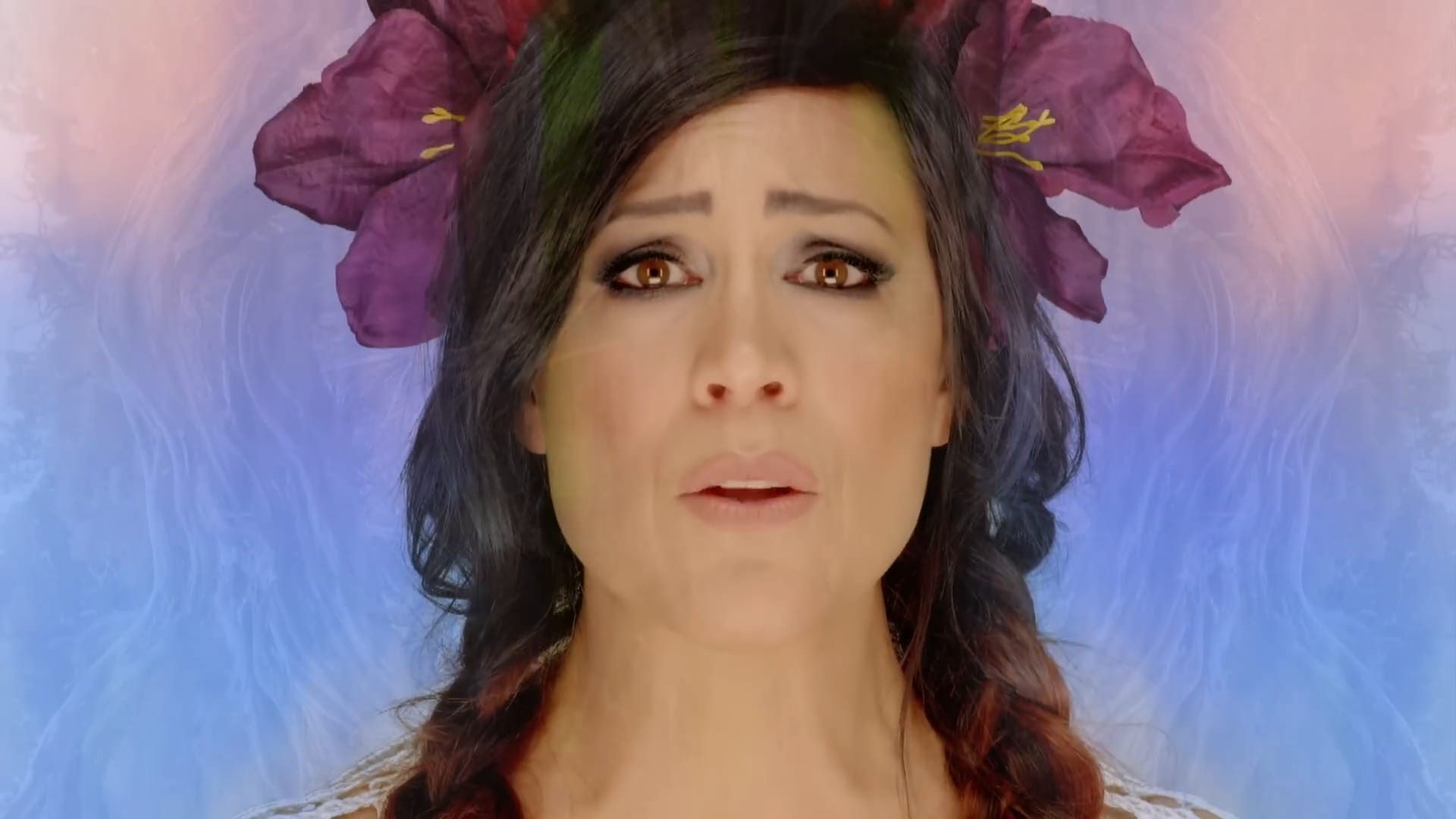 Kate Ceberano in close-up, wearing a crown of purple flowers against a soft pastel sky, mid-song.