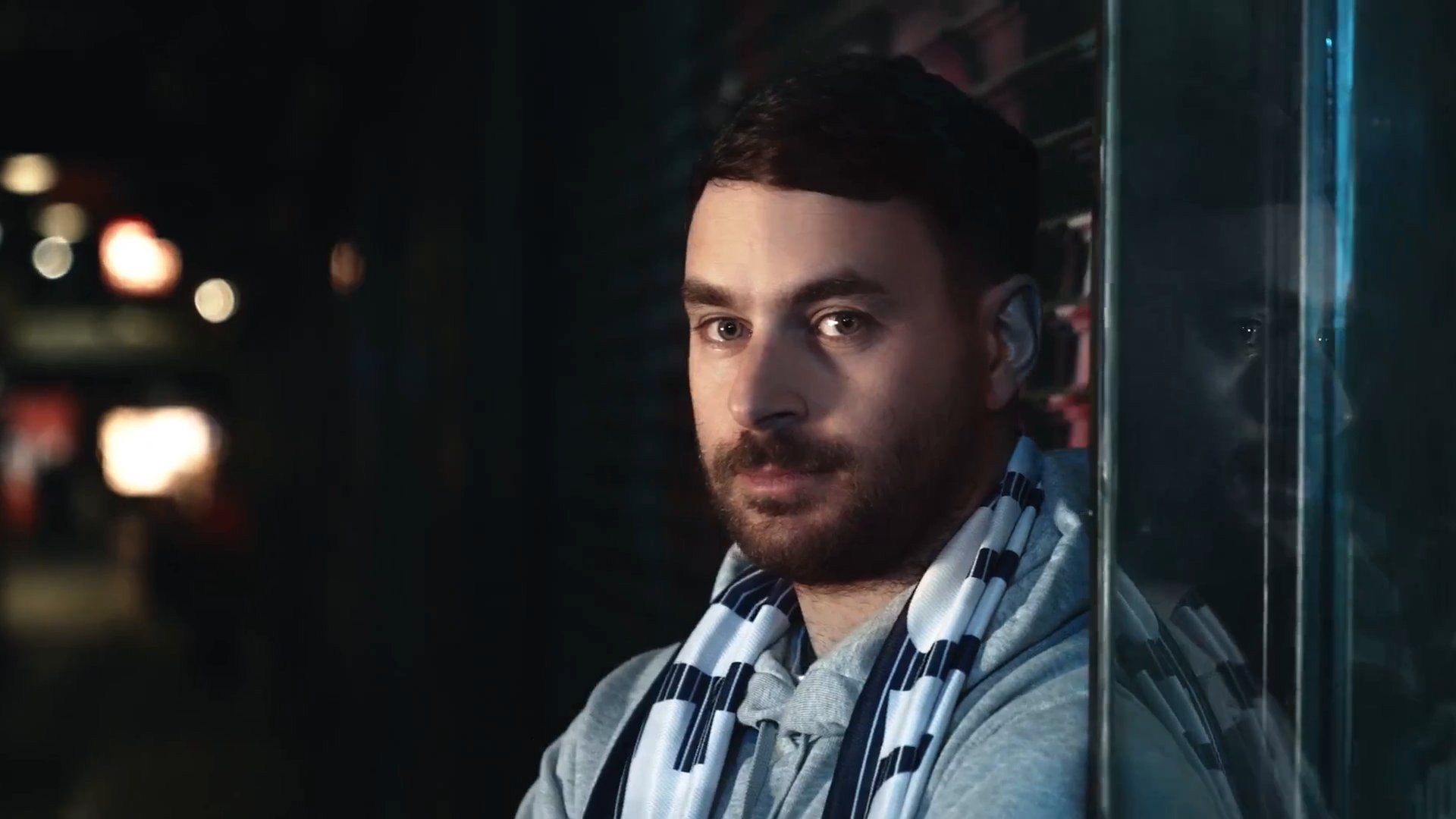 A Melbourne Victory supporter wearing a club scarf looks towards the camera.