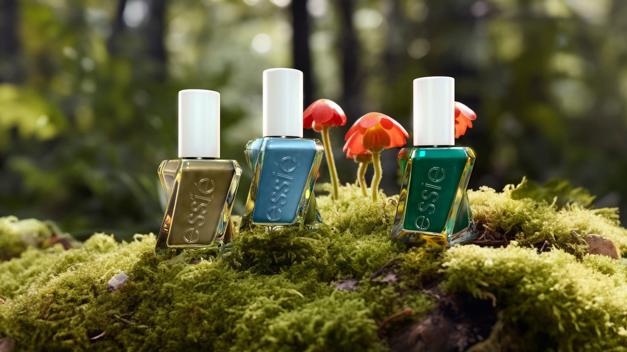 Three Essie bottles in olive, teal and green standing on green moss among small red-capped mushrooms, a soft forest behind.